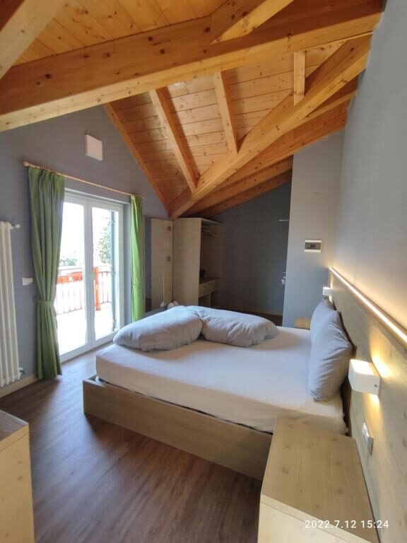 Spacious room with wooden beamed ceiling at Hotel Villa Argentina Ronzone
